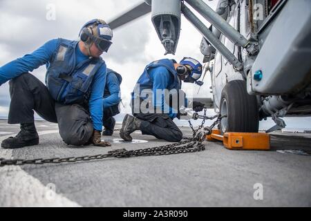 191004-N-HD110-1085 Mer de Chine du Sud (oct. 4, 2019) de cryptologie du technicien (technique) 2e classe Kristoffer Vergara, gauche, de Los Angeles, observe comme matelot de William Parker, de San Diego attache les chaînes à un MH-60S Sea Hawk, joint à l'Escadron d'hélicoptères de combat de la mer (HSC), 21 sur le pont de vol à bord du quai le navire de débarquement amphibie USS Harpers Ferry (LSD 49). Les Forces armées malaisiennes ont été rejoints par les Marines américains et les marins pour l'exercice Tiger 2019 grève où les forces canadiennes ont participé à la survie dans la jungle, d'assaut amphibie, raids aériens, et des services de soutien au combat traini Banque D'Images