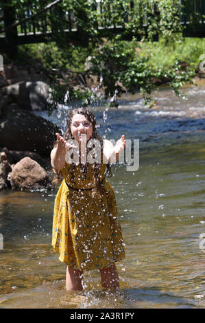 Girl splashing dans le ruisseau près d'un pont dans la région de Estes Park, Colorado Banque D'Images