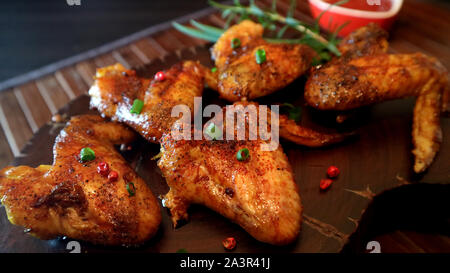 Rosted ailes de poulet et sauce sur fond de bois. Banque D'Images
