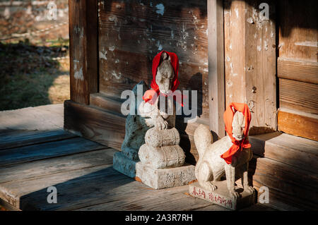 DEC 4, 2018 d'Aizu Wakamatsu, Japon - Japonais Kitsune Fox statue en pierre avec Red Hat et scarft au culte du Château Tsuruga - Close up détails face - Ja Banque D'Images