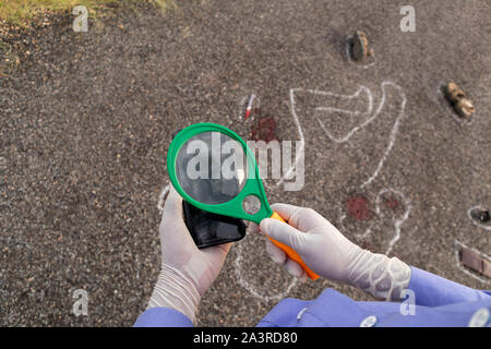 Enquêteur détective ou vérifier les empreintes digitales sur l'aide de mobile magnifier et Chalk outline corps mort comme arrière-plan. Banque D'Images