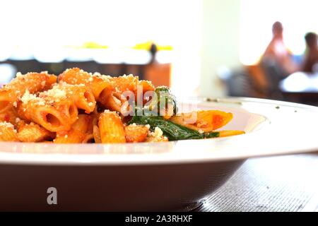 Pâtes Penne DANS LA SAUCE ARIABBATTA dans un bol blanc avec un fond bokeh Banque D'Images