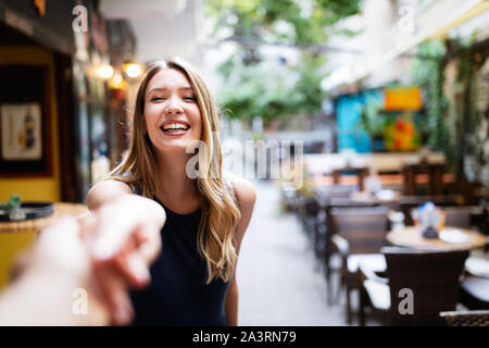 Portrait of happy young woman holding part de son petit ami en marchant Banque D'Images