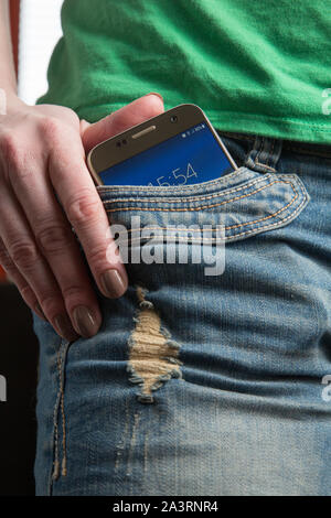 Mettre en main un téléphone cellulaire d'une poche de pantalon. Banque D'Images