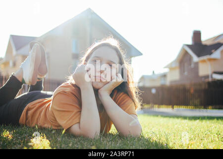 Portrait de pensée teen girl lying on grass vert ensoleillé de cottage village sur l'arrière-plan Banque D'Images