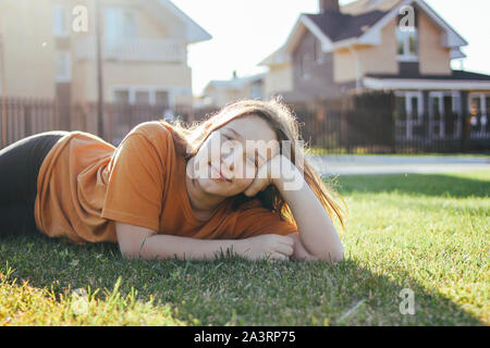 Portrait of smiling teen girl lying on grass vert ensoleillé de cottage village sur l'arrière-plan Banque D'Images