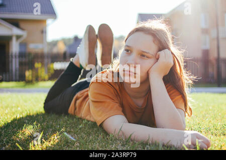 Portrait de pensée teen girl lying on grass vert ensoleillé de cottage village sur l'arrière-plan Banque D'Images