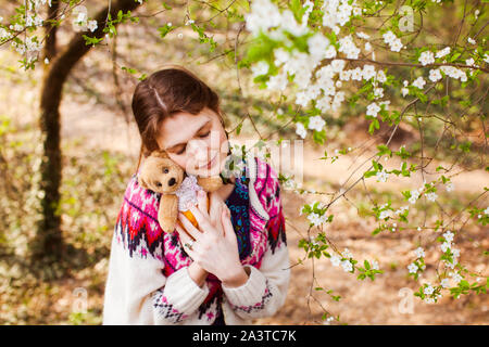 Sad girl jouet avec l'extérieur. Belle malheureux teenage girl with pigtails huggs bear toy Banque D'Images