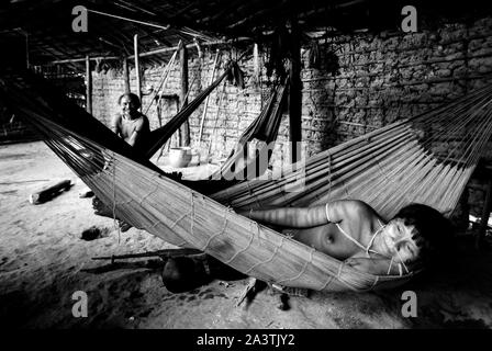 Le Brésil, l'Amazonie, Roraima : une famille se repose allongé sur les hamacs à l'intérieur du Shabono. Banque D'Images