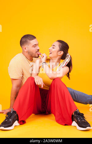 Beau jeune couple agissant silly dans studio sur fond jaune. Beau couple. Banque D'Images