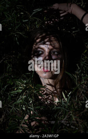 Jeune femme sérieuse peur halloween avec un miroir à l'intérieur des feuilles de nuit Banque D'Images