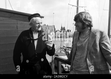 Älterer Herr dans landestypischer Tracht à Volendam im Gespräch mit einem jungen Mann, 1971. Les hommes portant le tableau typique de parler à un homme plus jeune dans la ville de Volendam, Pays-Bas 1971. Banque D'Images