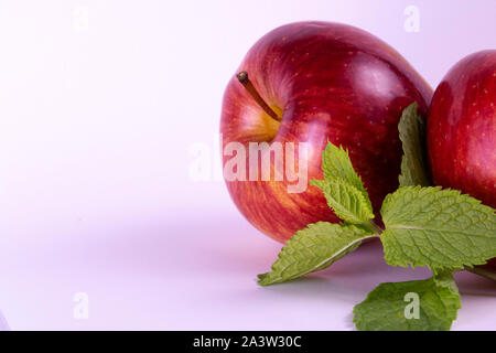 Pommes rouges sur fond blanc, les feuilles de menthe, groupe de deux Banque D'Images