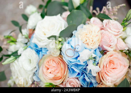Close-up of diamond suite nuptiale de mariage et bague de fiançailles placée à brides bouquet floral Banque D'Images