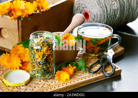 Le Calendula herb, un pot avec un mortier sec, marigold avec bouquet de fleurs fraîches, une tasse de tisane, de ciseaux et de fils de lin antique et une boîte de moi Banque D'Images