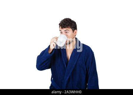 Portrait de jeune homme en retard porte peignoir bleu holding cup de café dans l'impossibilité de réveiller à temps pour se rendre au travail, isolé sur fond blanc. Banque D'Images