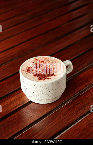 Tasse de chocolat chaud avec de la mousse de lait et saupoudré de cacao sur table en bois sur fond brun. Avec copyspace. Banque D'Images