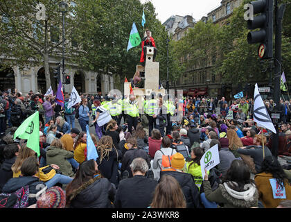 Les manifestants sur une structure en bois sur l'île de trafic entre Northumberland Avenue et le Strand à Trafalgar Square au cours de la quatrième journée d'une rébellion d'Extinction (XR) Manifestation à Westminster, Londres. Banque D'Images