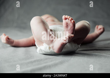 Nouveau-né bébé ventre et jambes en couche, couché sur un lit blanc, vue du dessus, copy space Banque D'Images