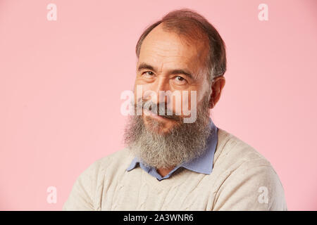 Close-up of young man with gray beard smiling at camera sur fond rose Banque D'Images