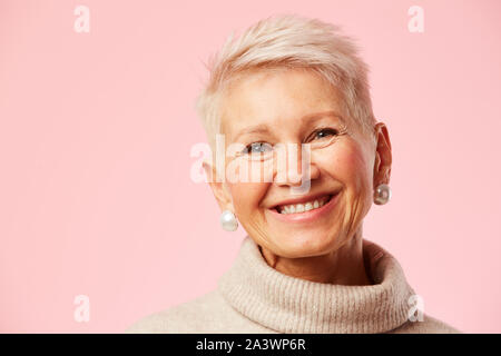 Portrait of beautiful happy young woman smiling at camera sur fond rose Banque D'Images