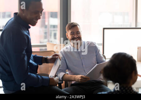 Smiling friendly groupe multiethnique collègues parler rire in office Banque D'Images