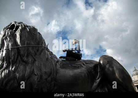 Un manifestant se trouve au sommet d'une statue à l'occasion de la manifestation à Trafalgar Square à Londres.Les manifestants sont descendus dans la rue dans le centre de Londres à travers cette semaine et la semaine prochaine pour mettre en surbrillance le "climat" d'urgence face à la planète. Banque D'Images