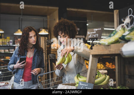 Les jeunes femelles adultes food shopping dans un magasin d'alimentation Banque D'Images