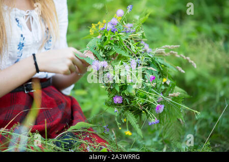 Pour la Couronne maison de Kupala. Mains tissent une couronne de fleurs sauvages et d'herbes. Banque D'Images