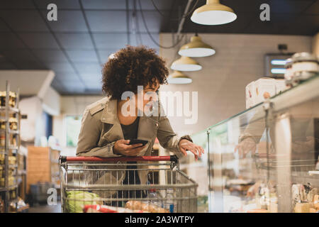 African American shopper à comptoir de charcuterie dans une épicerie Banque D'Images