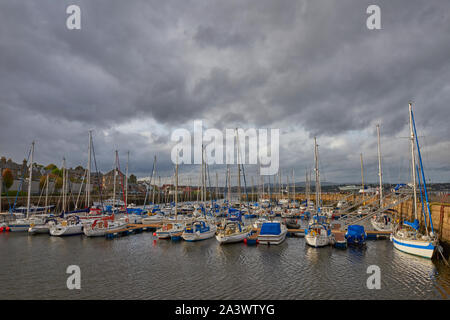 La petite ville de Tayport donnant sur son port où les yachts et bateaux à moteur sont amarrés dans la nouvelle marina, avec l'après-midi nuages menaçants com Banque D'Images