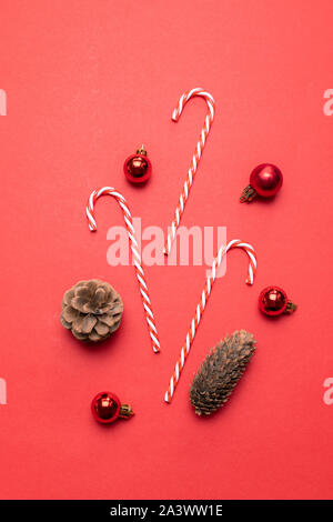 La composition créative avec des pommes de pins, des balles rouges et des bonbons caneson un fond rouge Vue de dessus pour Noël ou Nouvel an Banque D'Images