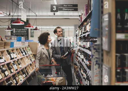 Couple choosing wine in grocery store Banque D'Images