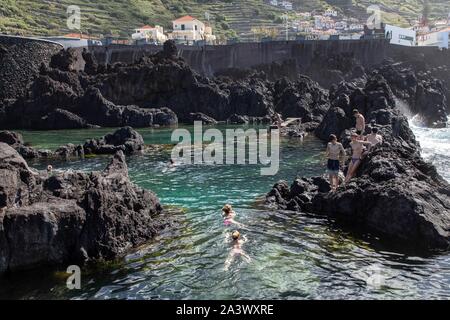 Les nageurs, les piscines naturelles dans la roche volcanique, Porto Moniz, île de Madère, Portugal Banque D'Images