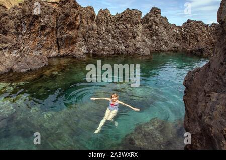 Les nageurs, les piscines naturelles dans la roche volcanique, Porto Moniz, île de Madère, Portugal Banque D'Images