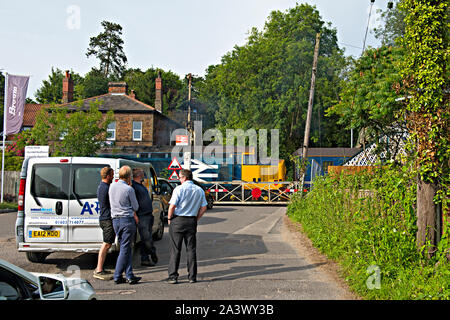 Pause sur la circulation le passage à niveau de la gare Brundall, Norfolk, Royaume-Uni. Une locomotive diesel de la classe 37 passe le passage à niveau. Banque D'Images