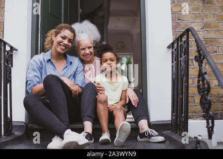 Trois générations de femmes assises à l'extérieur de la maison familiale Banque D'Images