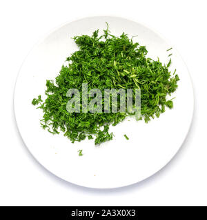 L'aneth vert coupé en petits morceaux sur une assiette blanche sur fond blanc. Banque D'Images