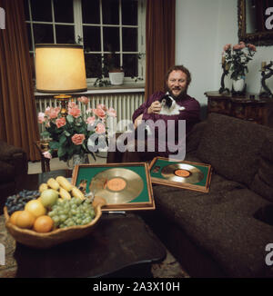 Der Deutsche Ivan Rebroff basse Sänger mit seinen Platten und Katze auf dem canapé , Weilstein Burg im Taunus Deutschland um 1975. Le chanteur Ivan Rebroff basse allemande avec ses dossiers et chat sur le canapé en Weilstein , château Taunus Allemagne autour de 1975. Banque D'Images