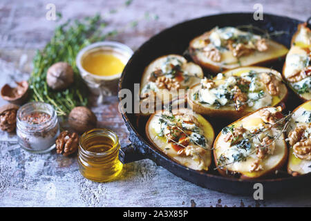 Poires au four avec du fromage bleu, miel et herbes. La cuisine française Entrée au vin. Focus sélectif. Macro. Banque D'Images