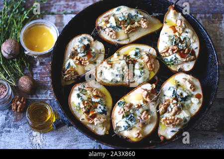 Poires au four avec du fromage bleu, miel et herbes. La cuisine française Entrée au vin. Focus sélectif. Macro. Banque D'Images