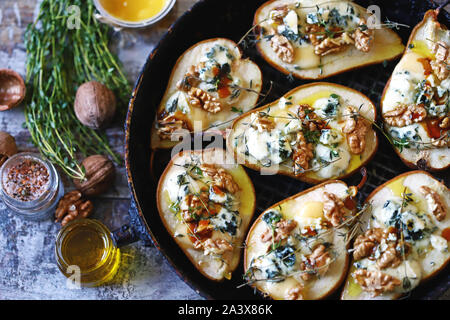 Poires au four avec du fromage bleu, miel et herbes. La cuisine française Entrée au vin. Focus sélectif. Macro. Banque D'Images