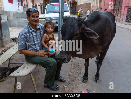 L'homme indien avec son enfant avec une vache dans la rue, du Rajasthan, Bikaner, Inde Banque D'Images