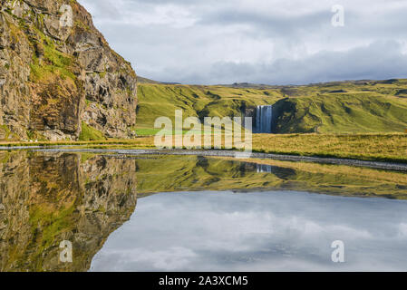 Cascade de Skogafoss de loin, avec réflexions d'eau, Islande. Banque D'Images