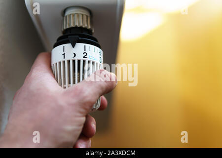 Main de l'homme réglage soupape thermostatique du radiateur jusqu'à la lune (nuit) icône, symbole pour économiser de l'argent à des frais de chauffage ou réglage de basse température, closeu Banque D'Images