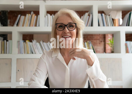 Smiling mature businesswoman having appel vidéo in office Banque D'Images