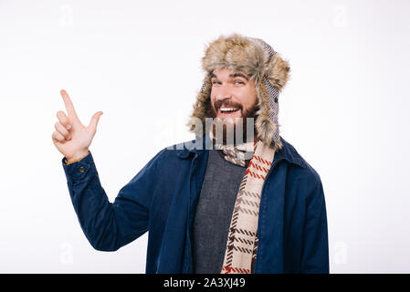 Un jeune homme barbu avec un chapeau et un foulard sur, dirigés à l'écart et souriant sur un fond blanc. Banque D'Images