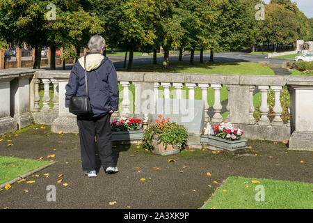 Senior woman looking at plaque commémorative dans le jardin commémoratif de Hillsborough, Port Sunlight, Royaume-Uni ; dédié aux supporters du Liverpool FC. Banque D'Images