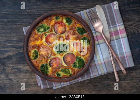 Frittata aux légumes avec bol en céramique, la nourriture végétarienne simple. La Frittata avec des œufs, de la tomate, le poivron, l'oignon, le brocoli et fromage,. Banque D'Images