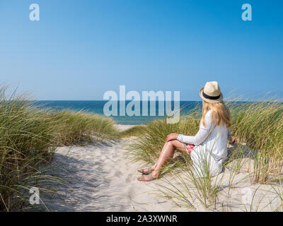 Femme assise dans le sable à regarder la mer Banque D'Images